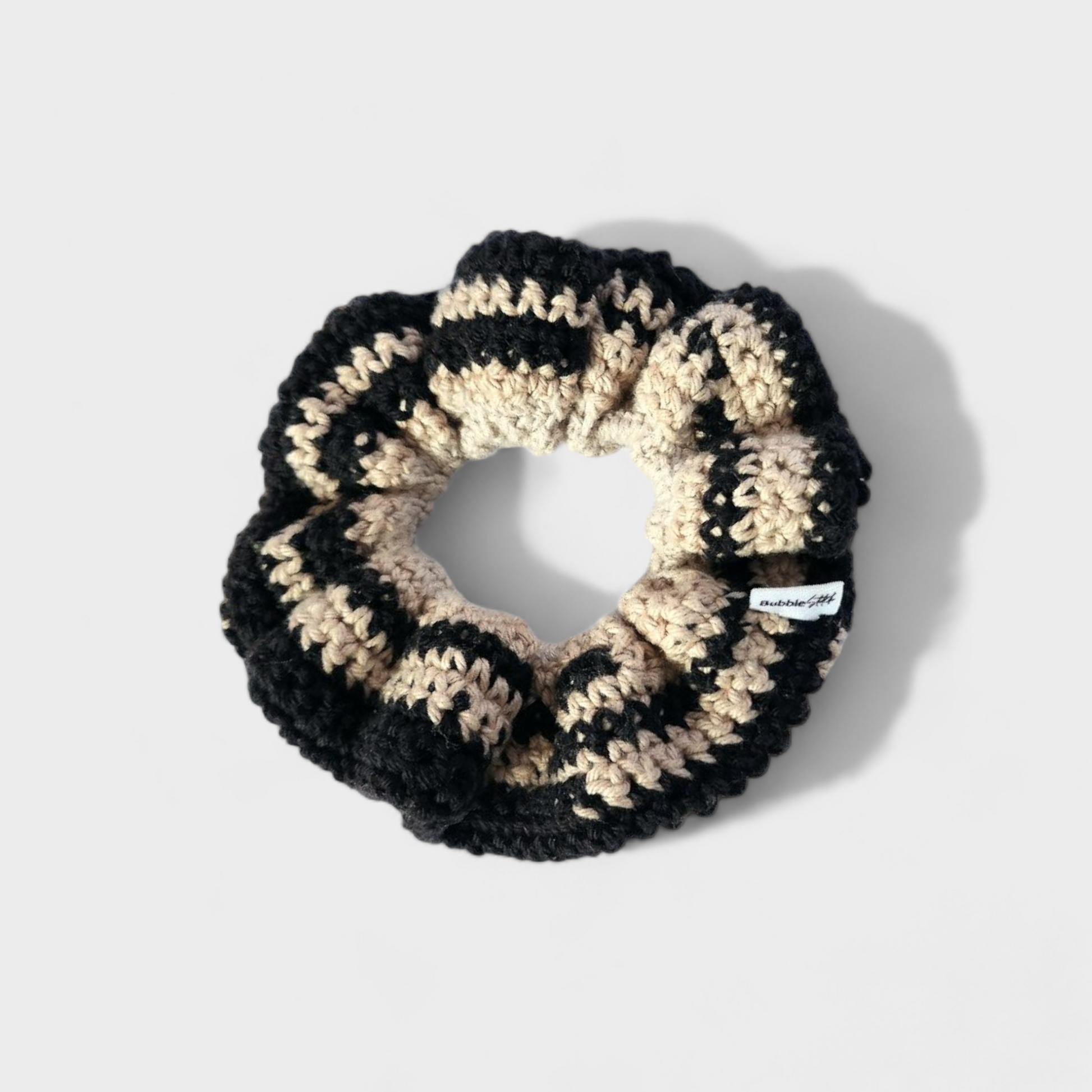 Scrunchie de croche numa mistura de preto e bege.