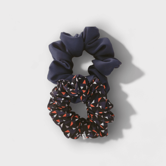 Duo de scrunchies  de cetim mate e seda chifon, um liso e um com padrão triangulos, ambos em tons de azul.